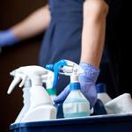 person holding a cleaning cart with various bottles and spray containers