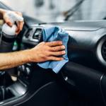 someone cleaning the interior of a car dashboard