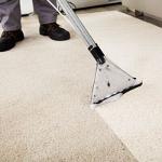 person using a carpet cleaning machine on light beige carpet